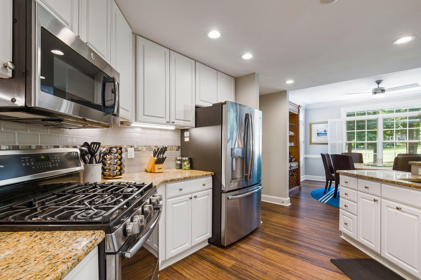 A finished kitchen with white shaker cabinets, granite countertops, a tiled backsplash and stainless steel appliances.